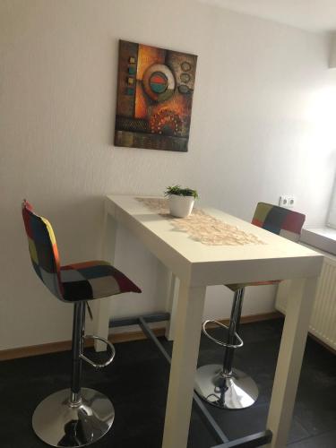 a white table with chairs and a painting on the wall at Ferienwohnung "Kleiner" EIFELTRAUM in Mettendorf