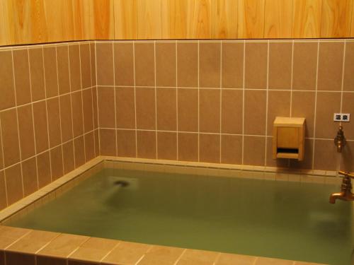 a bath tub in a bathroom with a soap dispenser at Pension Sanrinsha in Shizukuishi