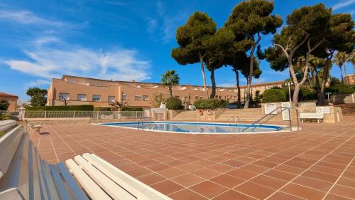 a swimming pool in a courtyard with trees and a building at EVH114 Casa con piscina comunitaria in Altafulla