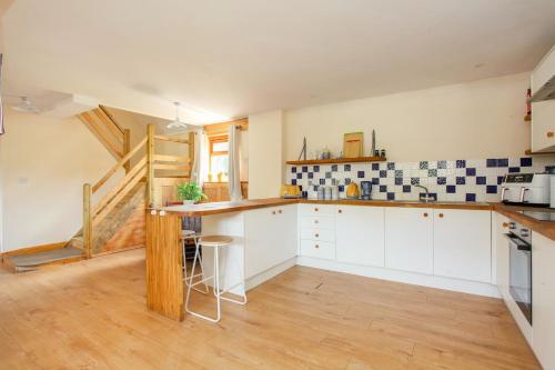 a kitchen with white cabinets and a wooden floor at Dulcie's Cottage in Wootton