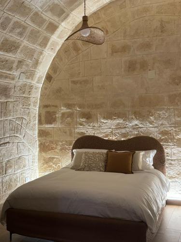 a bedroom with a large bed in a stone wall at Dimora Antica Santa Chiara in Trani