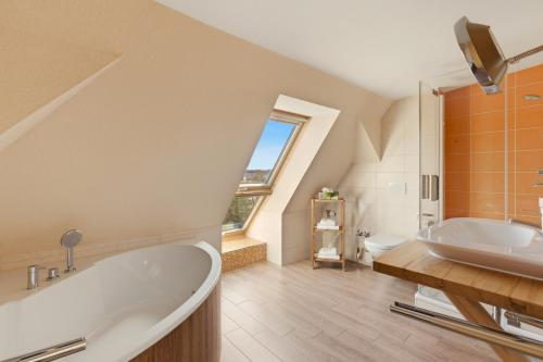 an attic bathroom with a tub and a sink at SONN IDYLL Aparthotel in Rathenow