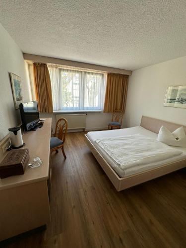 a bedroom with a bed and a desk with a computer at Hotel Aichtaler Hof in Grötzingen