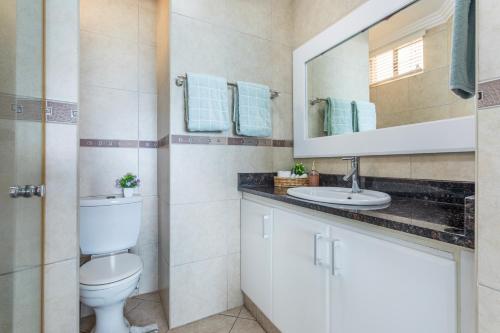 a bathroom with a toilet and a sink and a mirror at Sea View Luxury Penthouse in Ballito