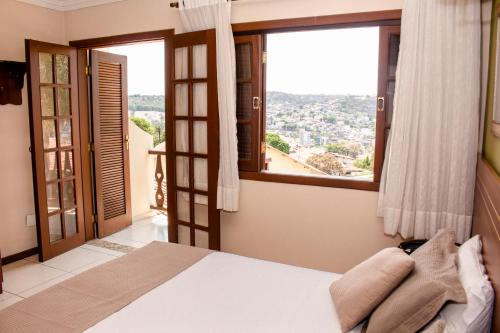 a bedroom with a bed and a large window at Hotel Dom Otto in Vespasiano