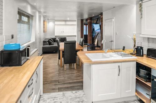 a kitchen and living room with a sink and a table at Central Manchester Family-Friendly Home with Free Parking and Workspace in Manchester