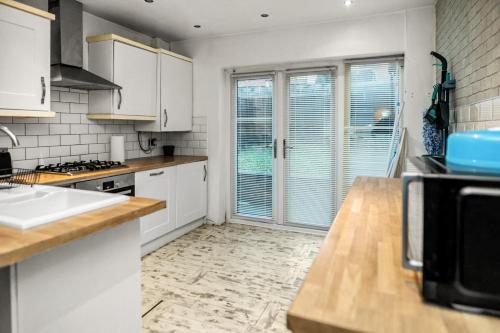 a kitchen with white cabinets and a large window at Central Manchester Family-Friendly Home with Free Parking and Workspace in Manchester
