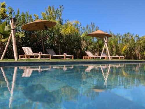 two chairs and umbrellas next to a swimming pool at Villa LaLa in Marrakesh