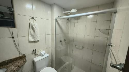 a bathroom with a shower and a toilet and a glass shower door at Apartamento térreo a 300 metros da praia de Itacimirim com piscina e jardim in Itacimirim