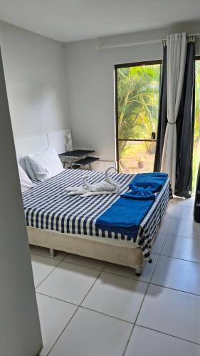 a bed in a room with a window and a bedvisor at Apartamento térreo a 300 metros da praia de Itacimirim com piscina e jardim in Itacimirim