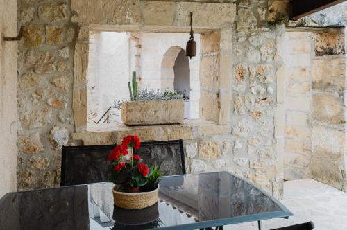 a glass table with a vase of flowers on a stone wall at Calvario Townhouse by rentavillamallorca in Pollença