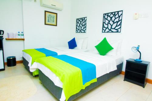 a bedroom with two beds and a lamp in it at Settle Inn Tourist Lodge in Kandy