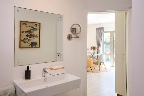 a white bathroom with a sink and a mirror at ocean10 Guesthouse in Cape Town