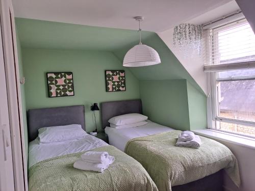 two beds in a room with green walls at Walkers Court By Treetop Property in Cirencester