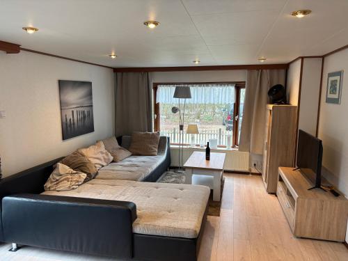 a living room with a couch and a television at Familienfreundliches Chalet E200 in Makkum Strandnah in Makkum