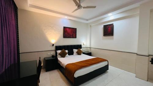 a bedroom with a bed and some paintings on the wall at Aadhar Hotel in Gurgaon