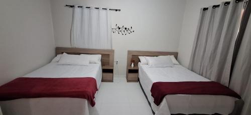 two beds in a room with white walls and windows at Casa em condominio com piscina na beira do rio Alegre in Santo Amaro