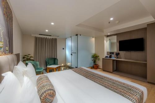 a hotel room with a bed and a flat screen tv at Hotel Shivashish in Ahmedabad