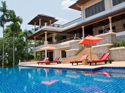 a house with a swimming pool with chairs and umbrellas at Villa Oriole in Layan Beach