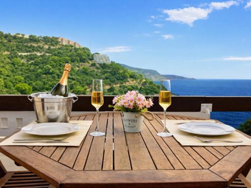 a wooden table with a bottle of wine and glasses at Luxury Duplex - 2 Terraces - Private Beach in Tossa de Mar