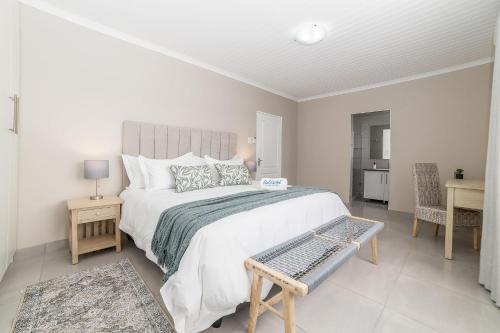 a white bedroom with a large bed and a desk at Uitzicht in Springbok