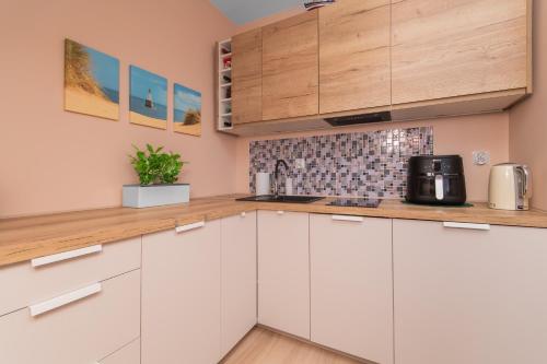 a kitchen with white cabinets and wooden counter tops at Apartament P27 in Sztutowo
