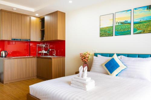 a bedroom with a white bed and a red kitchen at The Sea Light Hotel Phú Quốc- Sunset and Ocean View in Phú Quốc