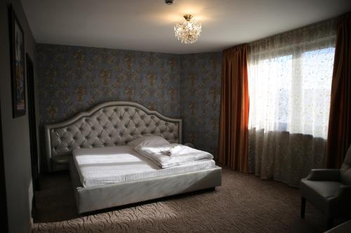 a bedroom with a bed and a chandelier at Hotel Kotva in Bratislava
