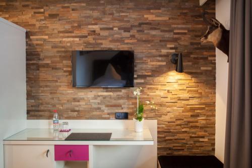 a room with a tv on a brick wall at Boutique Hotel Gams in Oberstdorf