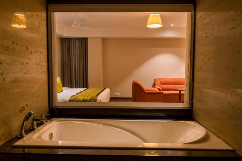 a bathroom with a bath tub and a bedroom at Lemon Tree Hotel Siliguri in Siliguri