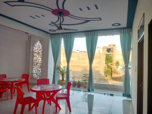 a dining room with red tables and chairs and a window at Keshav guest house in Rīngas