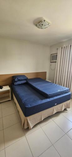 a bedroom with a bed with blue sheets on it at Boulevard suíte hotel suíte 1220 in Caldas Novas
