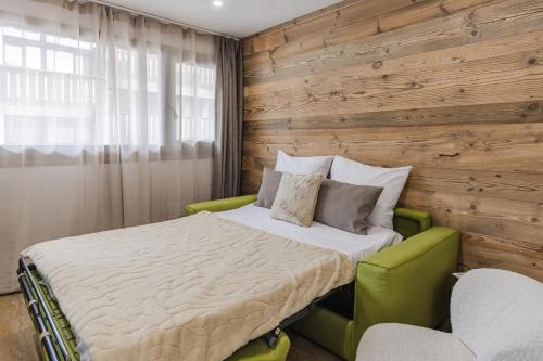 a bedroom with a bed and a green chair at Les Caribous - Lac 1 min, Espace Diamant, Megeve in Praz-sur-Arly