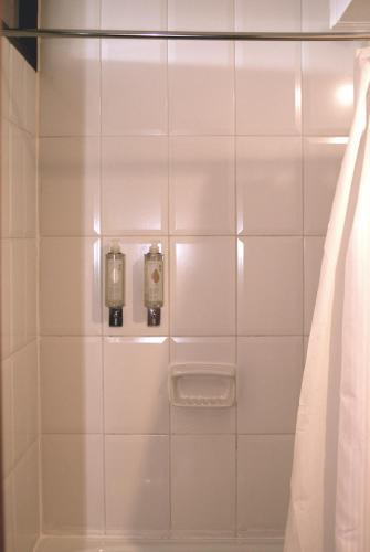 a white tiled shower with two lights and a curtain at Hotel Germania in Puerto Varas