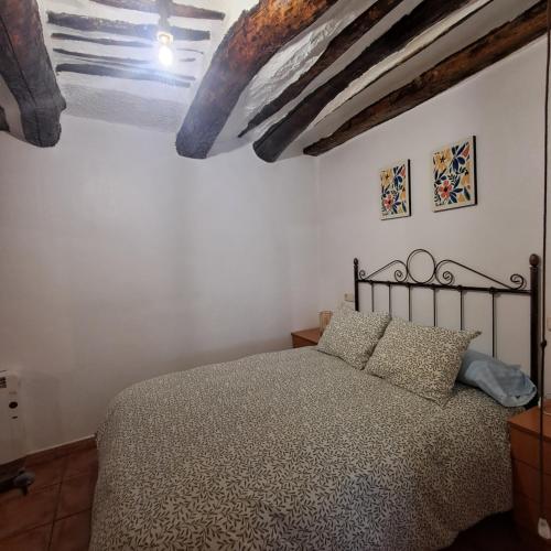 a bedroom with a bed and a ceiling with beams at La Casilla de la Fuente in Trevélez