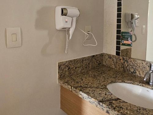 a bathroom with a sink and a phone on the wall at Boulevard suíte hotel suíte 1220 in Caldas Novas