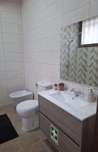 a white bathroom with a toilet and a sink at Cantinho do Lello in Bragança