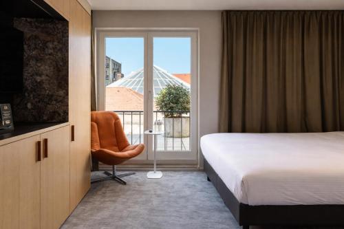 a hotel room with a bed and a window at Hotel Le Bois De Bruges in Bruges