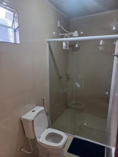 a bathroom with a toilet and a glass shower at Apartamentos da Lua in Barreirinhas