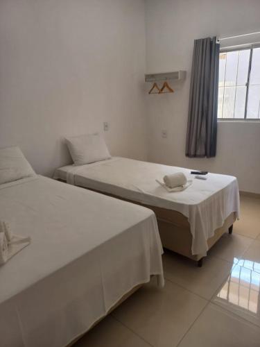 two twin beds in a room with a window at Apartamentos da Lua in Barreirinhas
