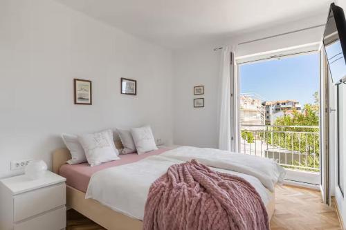 a white bedroom with a bed and a balcony at Holiday home with several apartments, a pool, sea views and a barbecue near Split in Podstrana