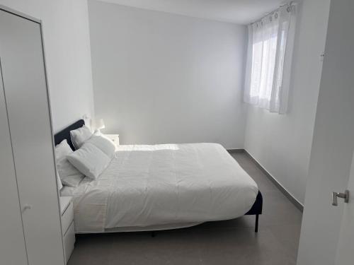 a white bedroom with a bed and a window at Casa Rural Las Vueltas in Mula