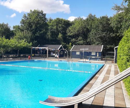 a large swimming pool with blue water and trees at Wellness villa Appelscha bij Drents-Friese Wold met sauna & whirlpool - VP048 in Hoogersmilde