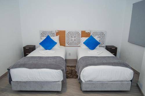 two beds in a room with blue pillows at Sunset Star II With Sea View in Calheta