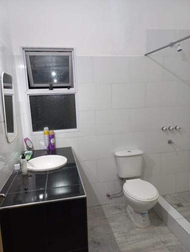 a white bathroom with a toilet and a sink at Los Horneros Zamba in Cerrillos