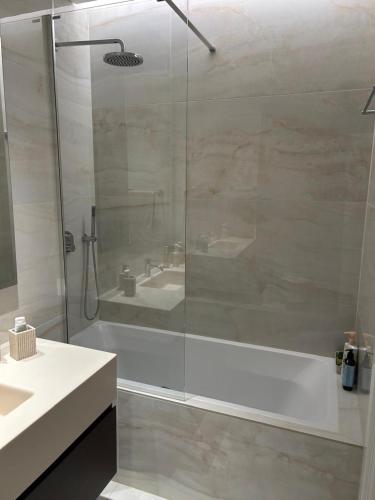 a bathroom with a shower and a tub and a sink at Trilogy Limassol East Tower Seafront Apartment in Limassol