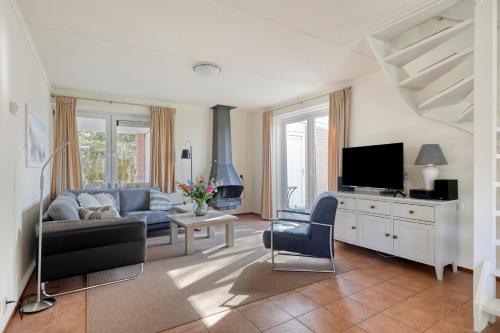 a living room with a couch and a tv at Holidayhouse Banjaard in Kamperland