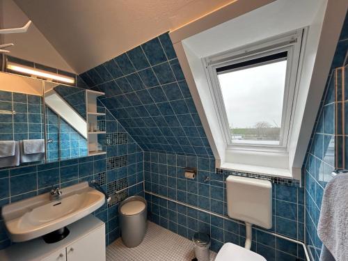a blue tiled bathroom with a sink and a window at Apartmenthaus am Watt Büsum in Büsum