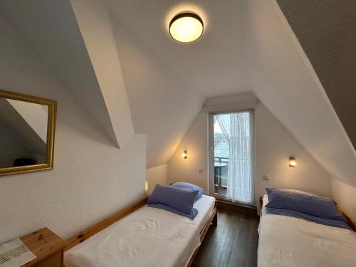 a attic room with two beds and a window at Apartmenthaus am Watt Büsum in Büsum