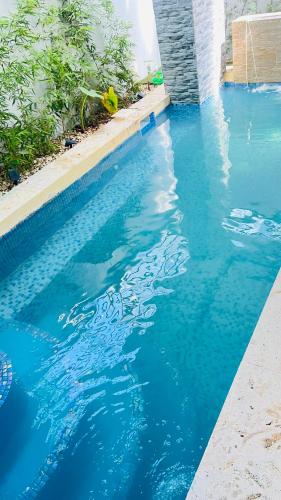 a pool of blue water next to a building at D Gomez House in Santiago de los Caballeros